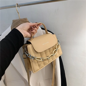 Detail of beige square crossbody bag featuring vertical embossing and a chunky chain strap