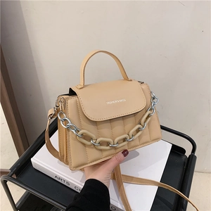 Detail of beige quilted shoulder bag with chunky chain decoration and logo print