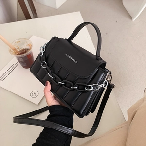 Detail view of black pleated crossbody bag with thick chain strap and top handle