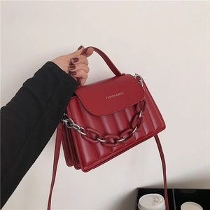 Detail of burgundy quilted crossbody bag with white logo and chunky chain strap