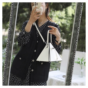 Détail du sac à main triangulaire blanc avec bords contrastés noirs et poignée supérieure