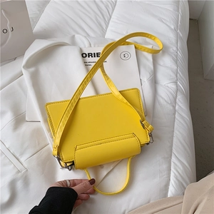 Close-up of bright yellow rectangular crossbody bag with leather texture and straps