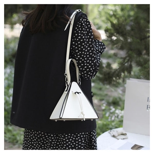 Photo extérieure d'un sac triangulaire blanc en cuir avec bords noirs et cordon de serrage