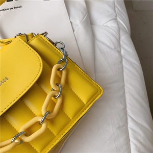 Detail of yellow quilted leather bag with thick chain decoration and BAGS inscription