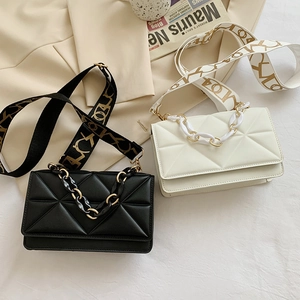 Detail of square quilted PU leather flap bags in black and white with wide fabric straps