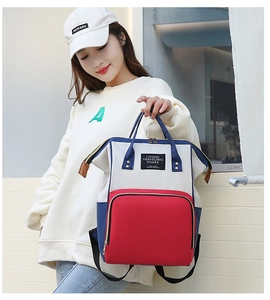 Détail du sac à dos en toile tricolore avec grande poche avant rouge et poignées robustes