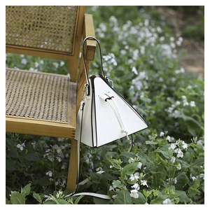 Détail d'un sac à main triangulaire blanc avec cordon de serrage sur une chaise en bois