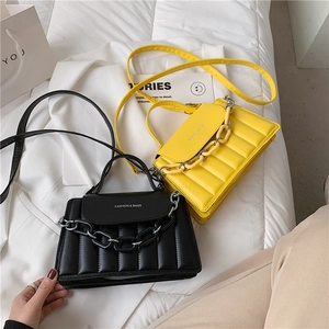 Detail of quilted leather crossbody bags with chunky chain straps on white bedsheet