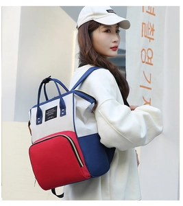 Vue latérale d'un sac à dos à langer tricolore porté par un mannequin en extérieur