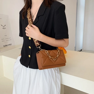 Detail view of brown quilted leather crossbody bag with jacquard strap and gold chain