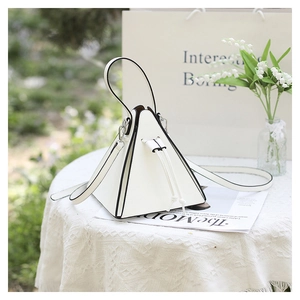 Détail du sac pyramide blanc avec bords noirs contrastés et design à cordon coulissant