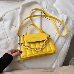 Close-up of bright yellow quilted shoulder bag with chunky chain and metal rings