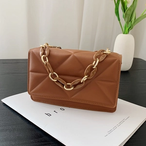 Detailed shot of brown quilted PU leather handbag with mixed resin and metal chain strap