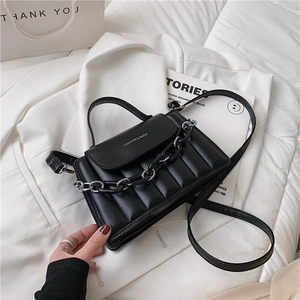 Detail of black quilted crossbody bag featuring silver chain and fashion text engraving