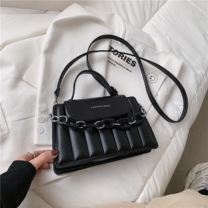 Detail of black quilted leather handbag with decorative resin and metal chain link strap