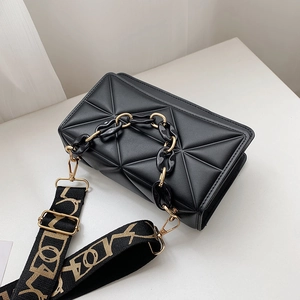 Detail of black quilted crossbody bag with geometric pattern and wide lettered strap