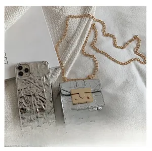 Gros plan du mini sac à chaîne argenté à motif crocodile à côté d'une coque