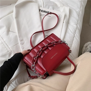 Detail of red quilted handbag with silver chain decoration and stylish text logo