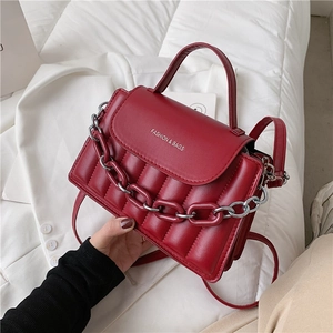 Close-up of wine red quilted handbag featuring silver chain detail and leather texture
