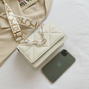 Detail of white quilted crossbody bag with acrylic chain and patterned wide strap