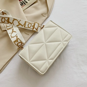 Detail of geometric quilted texture on cream crossbody bag with woven jacquard strap