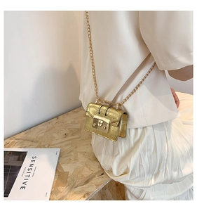 Détail d'un mini sac doré à chaîne avec texture crocodile et finition métallisée sur modèle