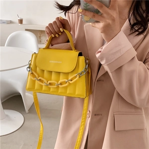 Detail of trendy yellow crossbody bag with fashion resin chain and PU leather finish