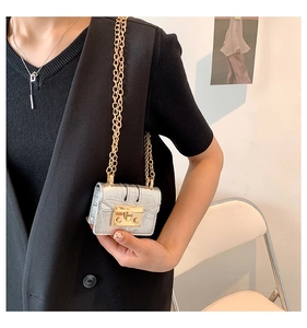 Détail d'un mini sac argenté avec texture crocodile et chaîne dorée sur mannequin