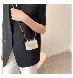Détail d'un mini sac argenté à motif crocodile avec bandoulière chaîne sur modèle