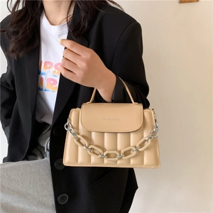Detailed shot of cream quilted handbag featuring resin chain and fashion logo