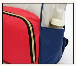 Détail du sac à langer tricolore avec poche frontale zippée et compartiment latéral