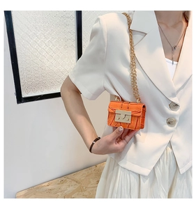 Detail of bright orange crocodile embossed mini bag with gold chain and metal lock