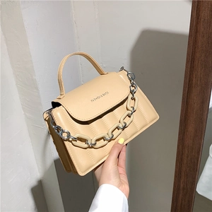 Close-up of beige quilted handbag with chunky plastic chain and fashion text logo