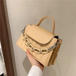 Detail of cream quilted crossbody bag with chunky resin chain and flap closure