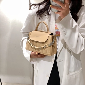 Detail of beige structured handbag with quilted texture and resin chain strap