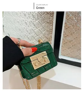 Gros plan du mini sac carré vert à motif crocodile avec fermoir et chaîne dorés