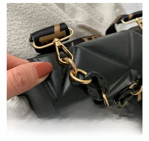 Detail of black geometric embossed leather bag with gold hardware and woven strap