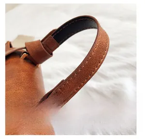 Détails de la poignée du sac en cuir marron avec texture litchi et métal doré