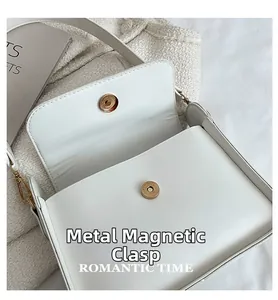 Close-up of the interior magnetic gold clasps on a white faux leather small square bag