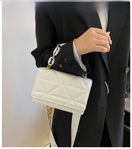 Detail of white quilted crossbody bag with geometric pattern and mixed chain strap
