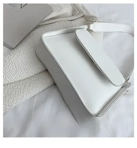 Top view of white baguette bag on white knit fabric with arts and crafts books