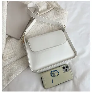 Size comparison of beige leather crossbody bag next to a smartphone showing dimensions