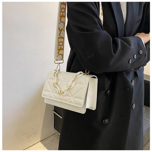 Detail of white quilted crossbody bag with golden chain and patterned wide shoulder strap