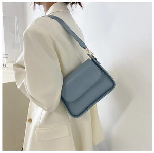 Side view of model wearing a light blue minimalist leather crossbody bag with gold hardware