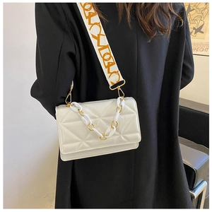 Detail of white quilted crossbody bag with golden chain and orange lettered wide strap