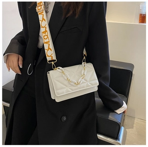 Detail of white quilted crossbody bag with acrylic chain and abstract patterned strap