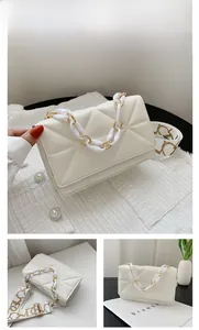 Detail of white quilted handbag featuring a chunky chain and printed wide strap
