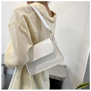 Close-up of a minimalist white crossbody bag with smooth leather and gold metal buckle