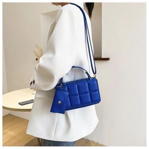 Close-up of blue quilted small square bag with matching mini charm purse and gold hardware