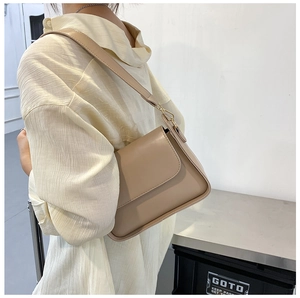 Close-up of camel brown crossbody bag with flip cover and golden metallic hardware